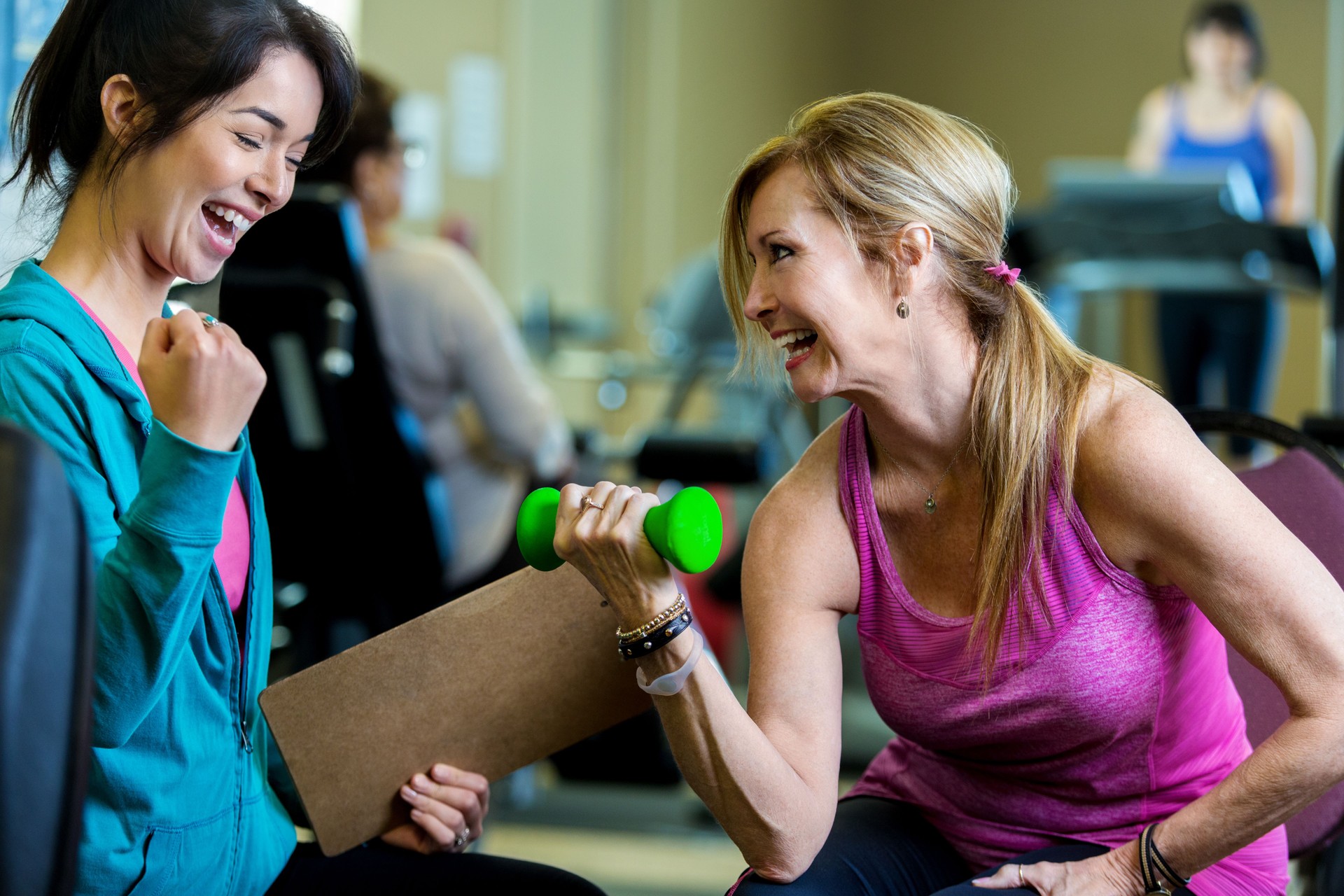 Excited personal trainer coaches senior female client